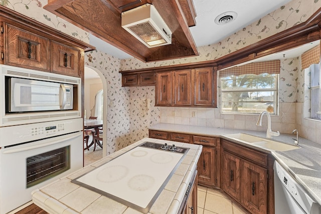 kitchen with backsplash, white appliances, sink, and light tile patterned floors