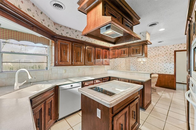 kitchen featuring dishwasher, a center island, sink, stovetop, and light tile patterned flooring