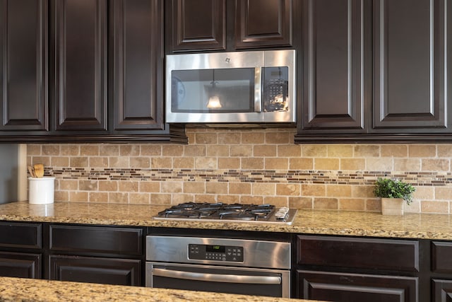 kitchen with backsplash, dark brown cabinetry, light stone counters, and stainless steel appliances