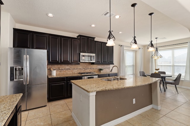 kitchen with stainless steel appliances, a kitchen island with sink, hanging light fixtures, and sink