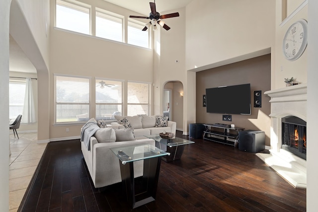 living room with hardwood / wood-style floors, ceiling fan, and a high ceiling