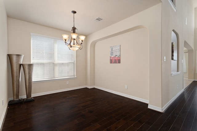 unfurnished dining area featuring a notable chandelier and dark hardwood / wood-style floors