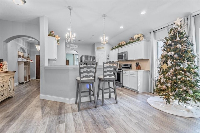 kitchen featuring white cabinets, a kitchen bar, stainless steel appliances, and light hardwood / wood-style flooring