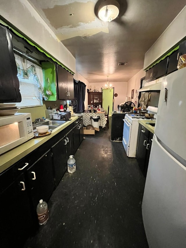 kitchen featuring pendant lighting, a notable chandelier, white appliances, and sink