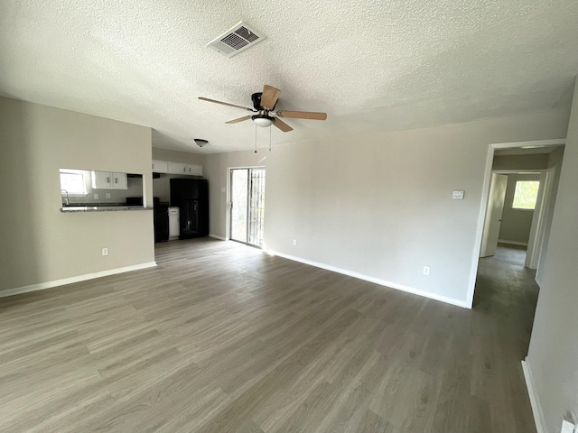 unfurnished living room with wood-type flooring, a textured ceiling, and ceiling fan