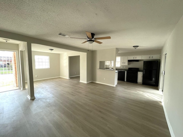 unfurnished living room with ceiling fan, a textured ceiling, and light wood-type flooring