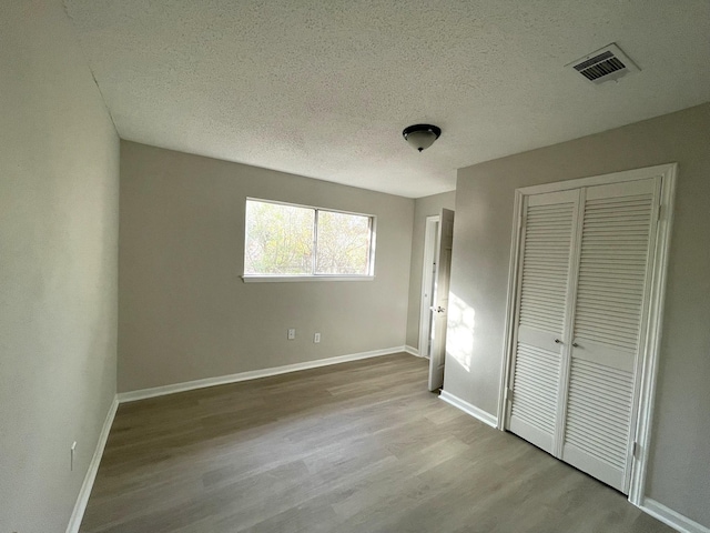 unfurnished bedroom with a closet, light hardwood / wood-style floors, and a textured ceiling