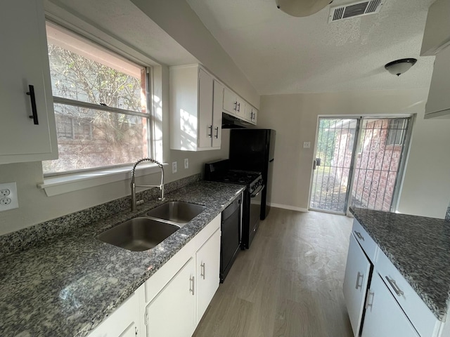 kitchen with white cabinetry, sink, a healthy amount of sunlight, black appliances, and light wood-type flooring