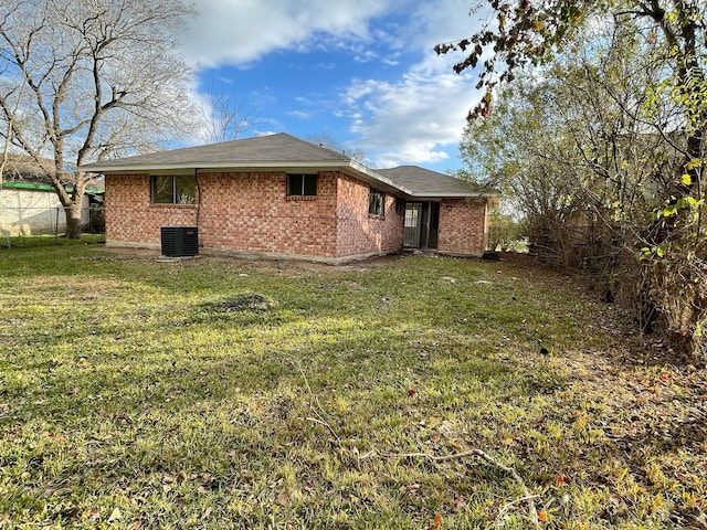 rear view of property featuring cooling unit and a lawn