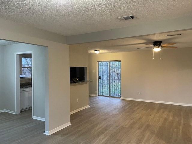 empty room with ceiling fan, hardwood / wood-style floors, and a textured ceiling