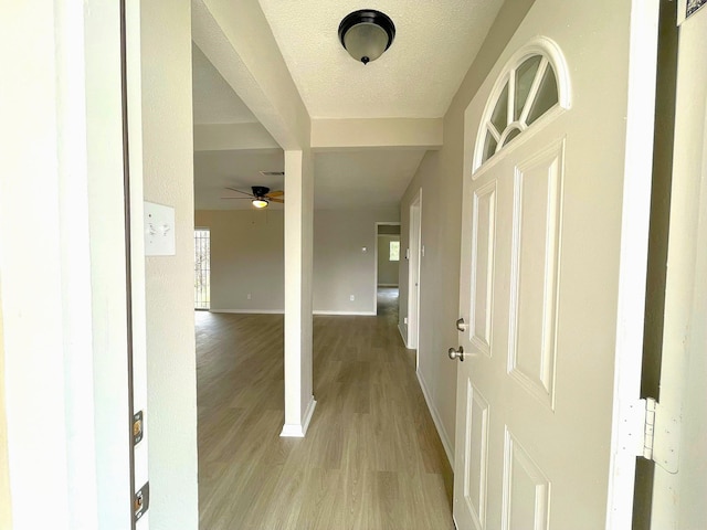 entryway featuring a textured ceiling, light wood-type flooring, and ceiling fan