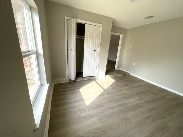 unfurnished bedroom with multiple windows, hardwood / wood-style flooring, and a closet