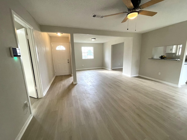 unfurnished living room featuring ceiling fan, a textured ceiling, and light hardwood / wood-style flooring