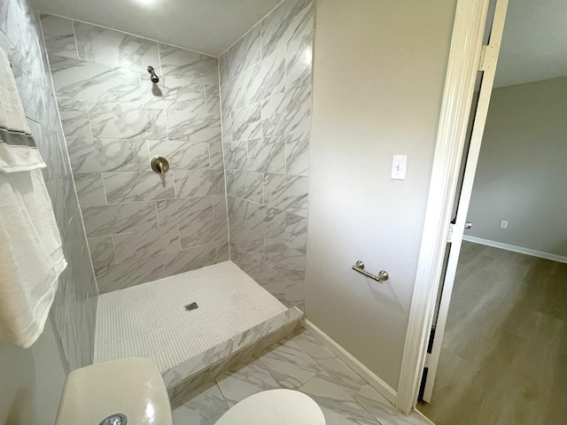 bathroom featuring a tile shower and toilet