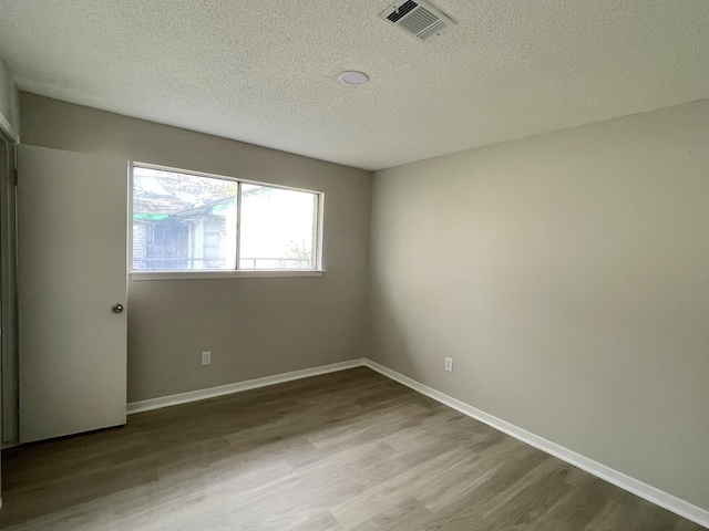 empty room with hardwood / wood-style floors and a textured ceiling