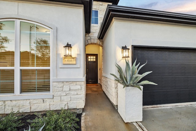 exterior entry at dusk featuring a garage