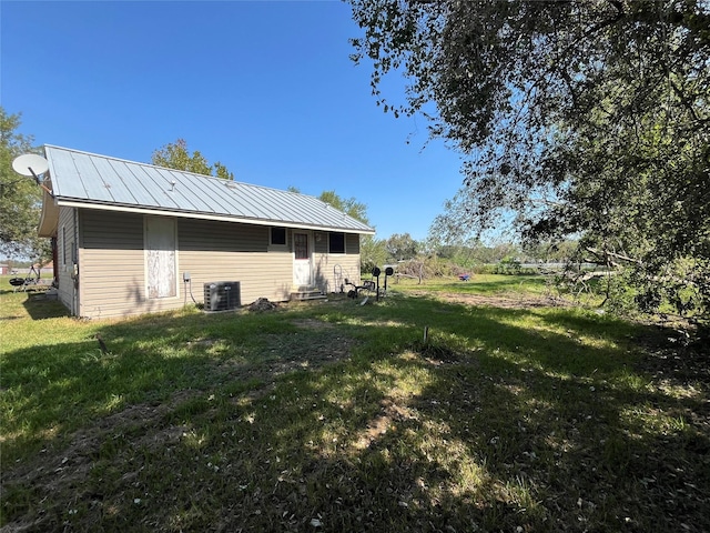 exterior space featuring central air condition unit and a lawn