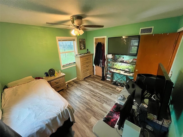 bedroom featuring ceiling fan, light wood-type flooring, a spacious closet, and a closet