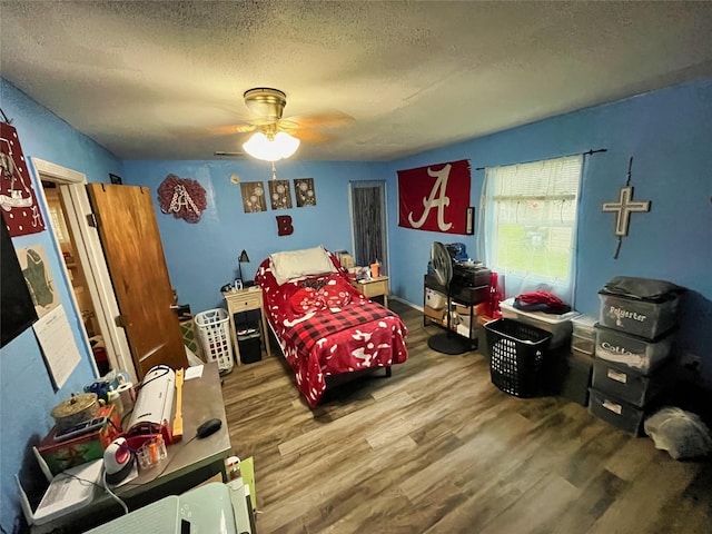 bedroom with a textured ceiling, hardwood / wood-style flooring, and ceiling fan