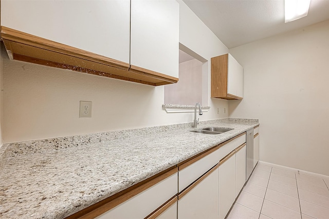 kitchen with white cabinetry, sink, light tile patterned flooring, and stainless steel dishwasher