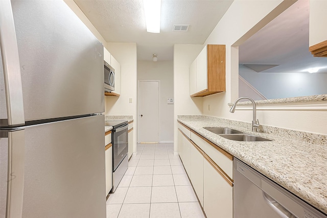 kitchen featuring white cabinets, light tile patterned flooring, sink, and appliances with stainless steel finishes