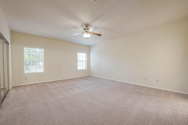 carpeted spare room featuring plenty of natural light and ceiling fan