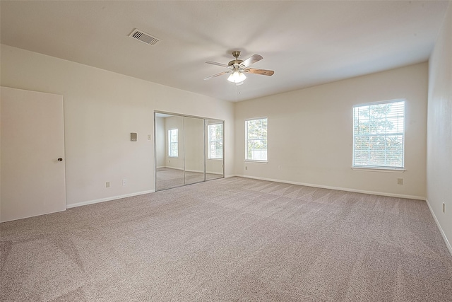 carpeted spare room featuring plenty of natural light and ceiling fan