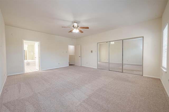 unfurnished bedroom featuring a closet, ceiling fan, light colored carpet, and ensuite bathroom