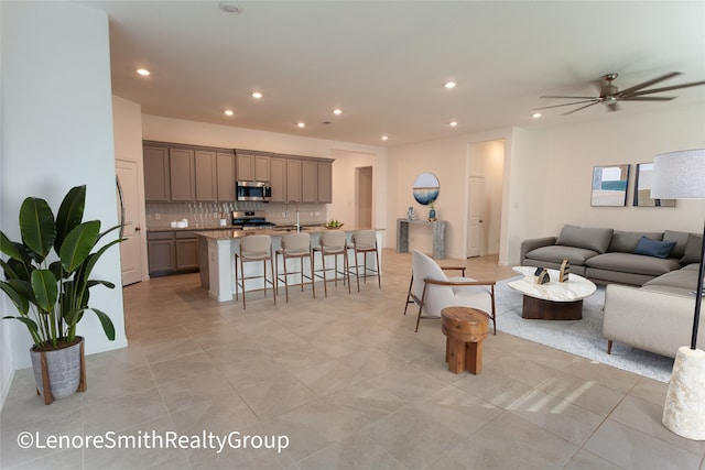 living room featuring light tile patterned floors, ceiling fan, and sink