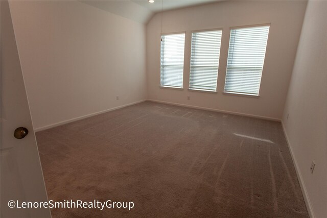 unfurnished room featuring dark carpet and vaulted ceiling