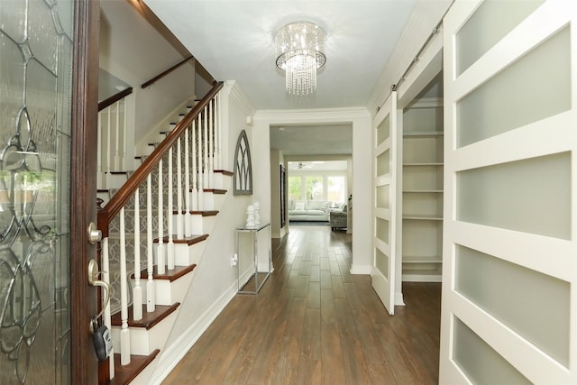 foyer entrance featuring a barn door, an inviting chandelier, and dark hardwood / wood-style flooring