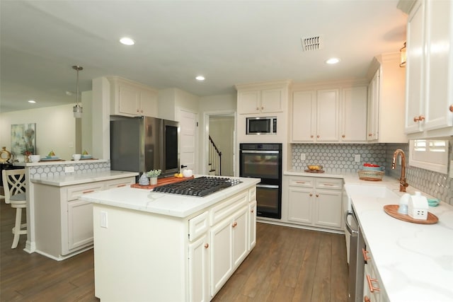 kitchen with pendant lighting, light stone counters, a center island, and appliances with stainless steel finishes