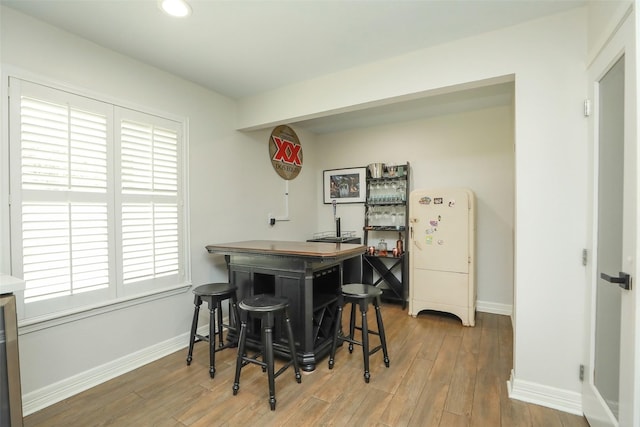 dining area featuring hardwood / wood-style floors and bar area