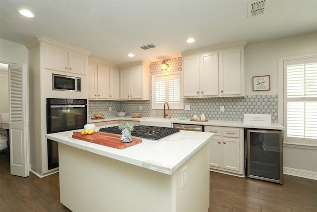 kitchen featuring wine cooler, white cabinetry, appliances with stainless steel finishes, and a kitchen island