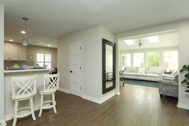 kitchen with pendant lighting, dark hardwood / wood-style floors, a kitchen breakfast bar, and backsplash