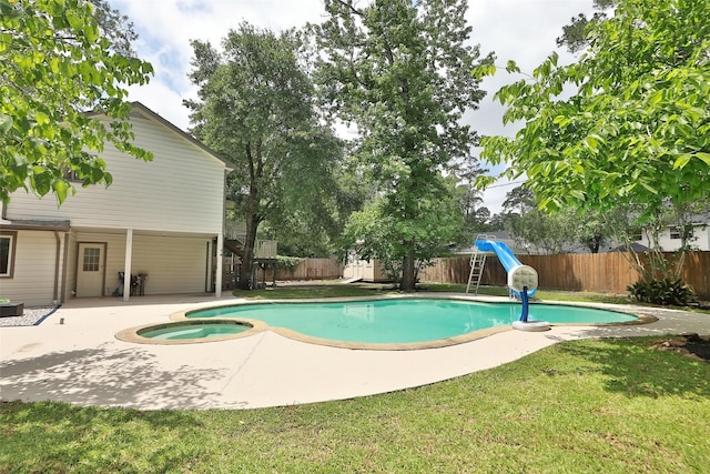 view of pool with an in ground hot tub, a water slide, a yard, and a patio area