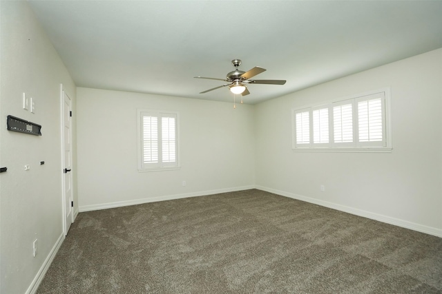 spare room featuring ceiling fan and dark colored carpet