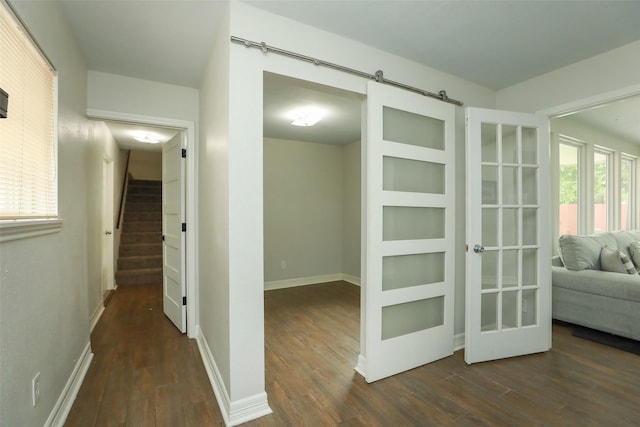 hallway with a barn door and dark hardwood / wood-style flooring