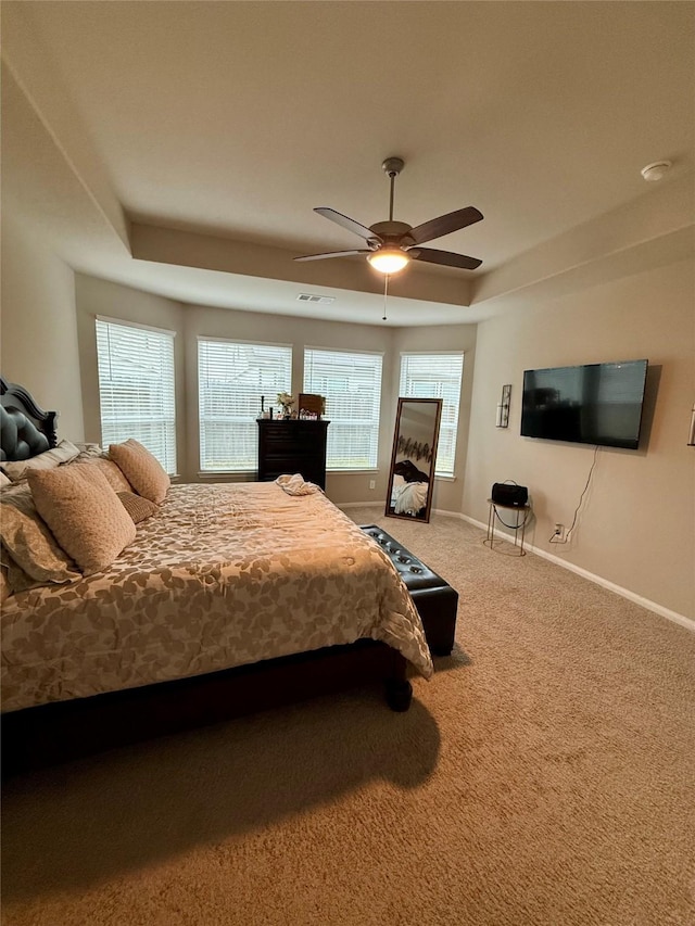 carpeted bedroom featuring a raised ceiling and ceiling fan