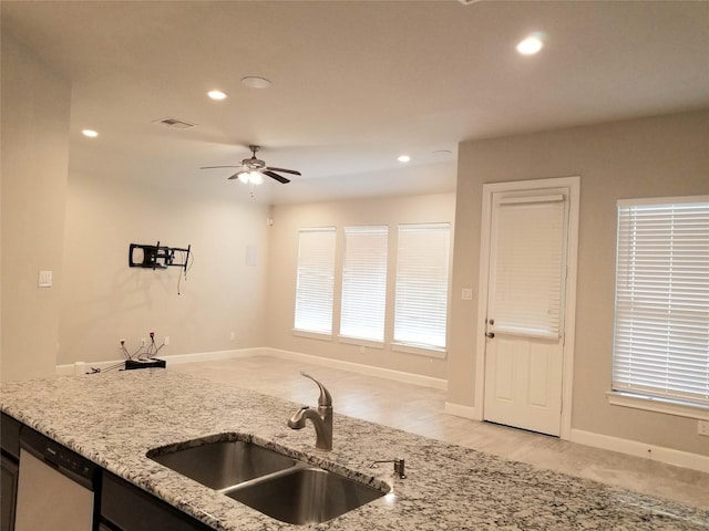 kitchen featuring ceiling fan, dishwasher, light stone counters, and sink