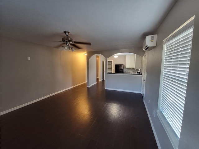 unfurnished living room with a wall mounted air conditioner, dark hardwood / wood-style floors, and ceiling fan