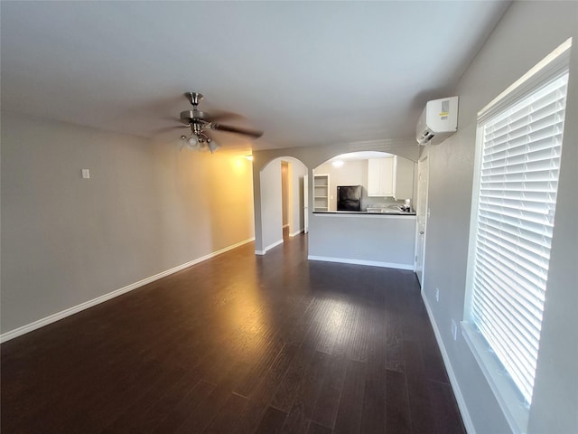 unfurnished living room featuring a wall unit AC, a wealth of natural light, dark hardwood / wood-style flooring, and ceiling fan