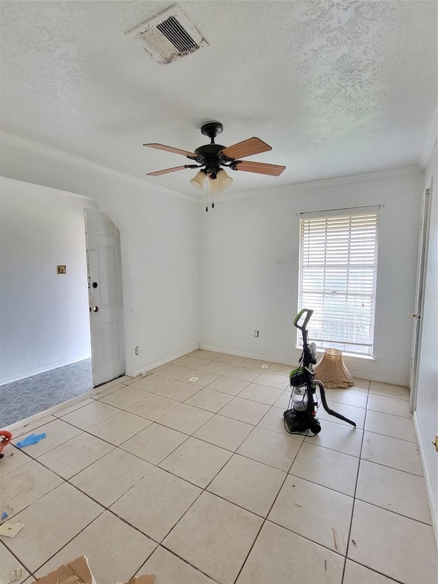 tiled spare room featuring ceiling fan, crown molding, and a textured ceiling