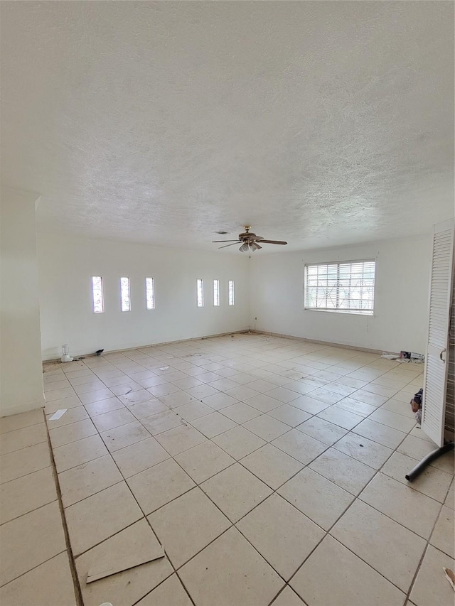 tiled empty room featuring ceiling fan and a textured ceiling