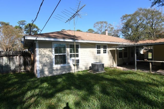 rear view of property featuring central AC unit and a lawn