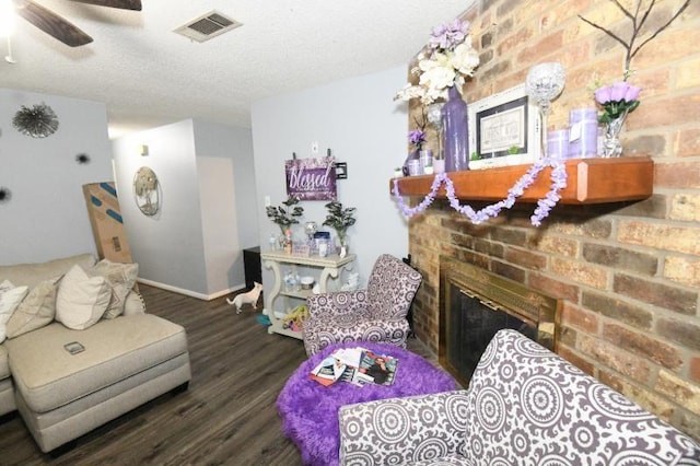 living room with ceiling fan, dark wood-type flooring, a textured ceiling, and a brick fireplace