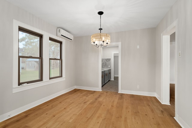 unfurnished room with a chandelier, light wood-type flooring, and a wall unit AC