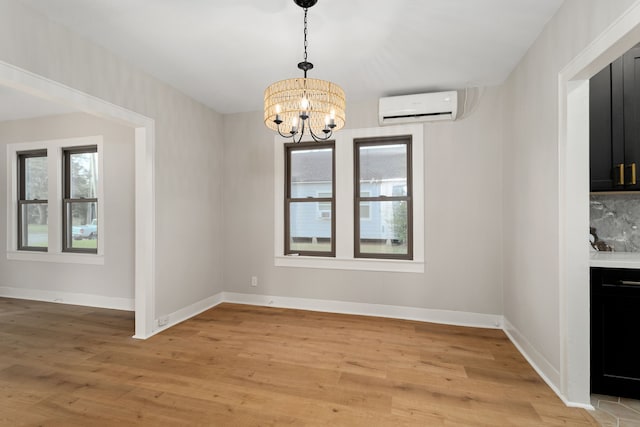 unfurnished dining area with a chandelier, light wood-type flooring, and an AC wall unit