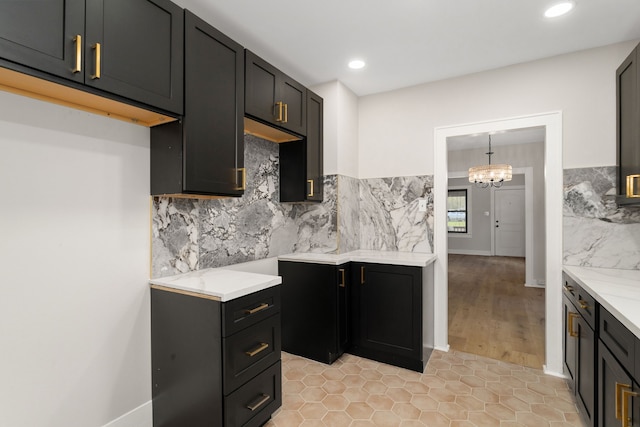 kitchen featuring light stone countertops, hanging light fixtures, a chandelier, decorative backsplash, and light tile patterned flooring