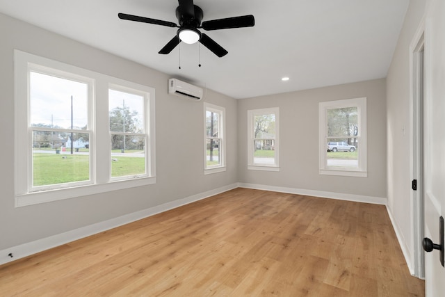 unfurnished room featuring light hardwood / wood-style flooring, a wall mounted AC, and ceiling fan